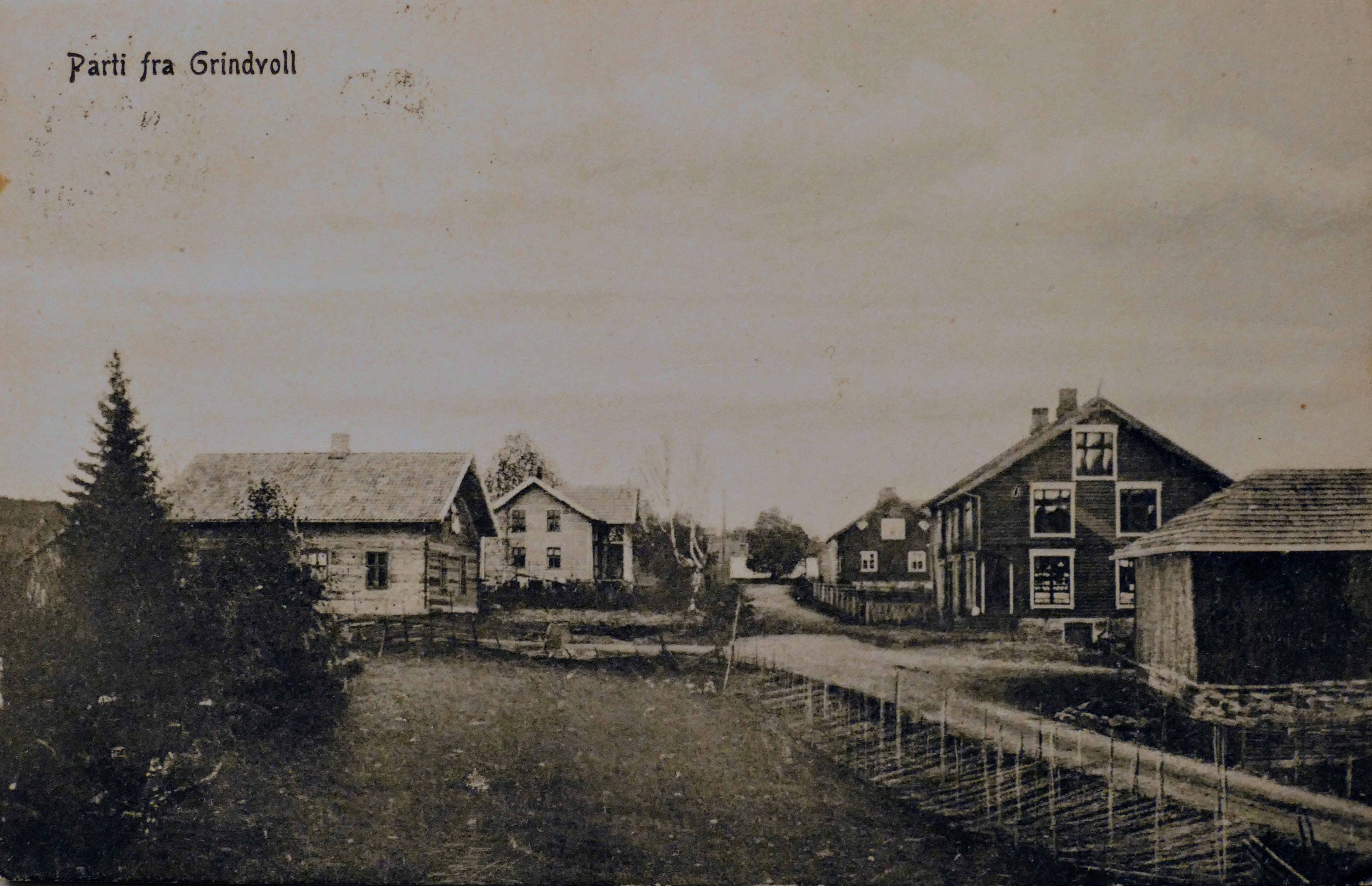Stua Grinen, til venstre i bildet, finner vi på kart fra 1827. Denne stua kan være Grindvolls eldste bygning. Bygningen slik vi ser den i dag, ble reist rundt denne tømmerstua. Prospektkortet er utlånt av Brit B. Ballangrud.