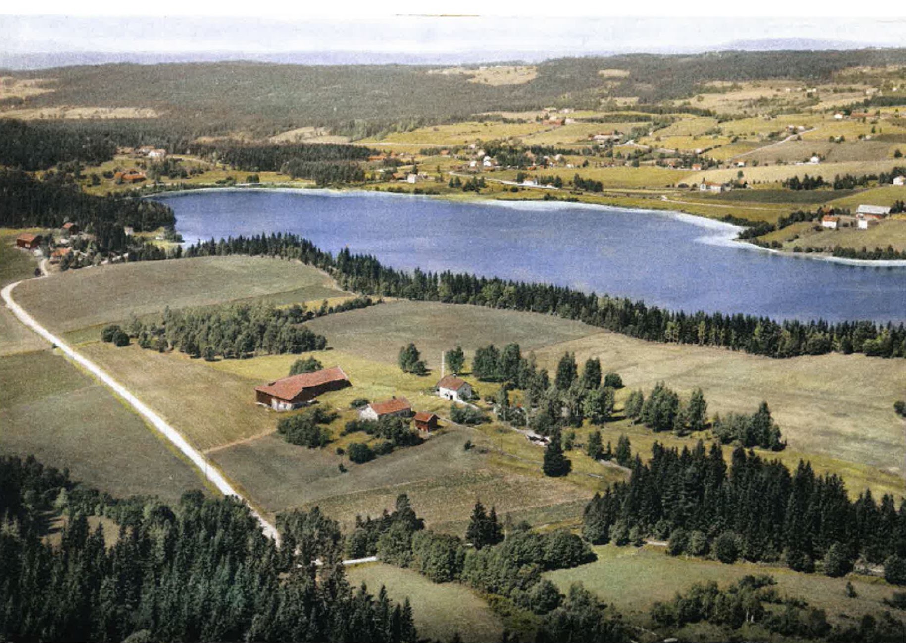Bildet tatt er tatt ca. 1954 og viser vannet med garden Vassjø i forgrunnen. Den gang var det lite rørsiv langs nordsiden, kun begrensede mengder utenfor stasjonen. Foto utlånt av Marte og Kim Skaug.